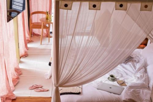 a bedroom with a canopy bed with pink curtains and slippers at Sumba Lodge in Manuel Antonio