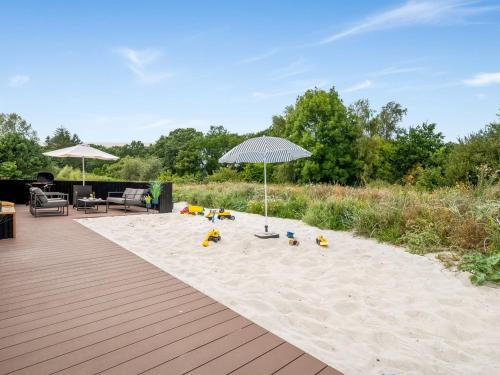 a sandy beach with an umbrella and chairs at Holiday Home Artur - 800m from the sea by Interhome in Fjellerup