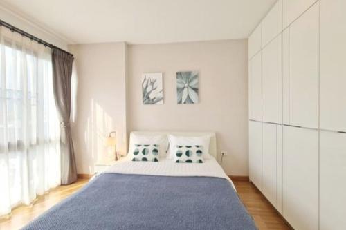 Un dormitorio con una cama grande y una ventana grande. en Stay Nimman Center with Rooftop Pool, en Chiang Mai