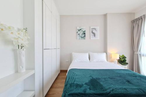 een witte slaapkamer met een groene deken op een bed bij Lovely 1BR with Rooftop Pool in Nimmanhemin 605 in Chiang Mai