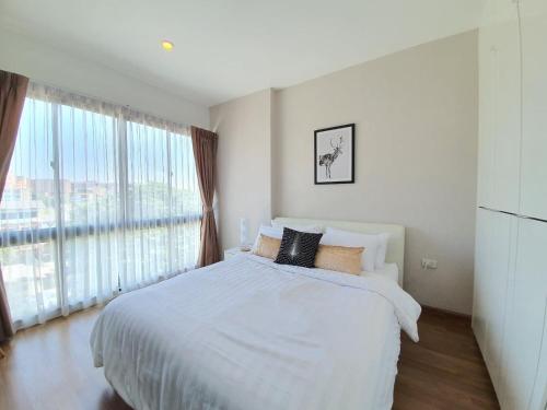 een witte slaapkamer met een bed en een groot raam bij Live in Nimman High Floor And Rooftop Pool in Chiang Mai