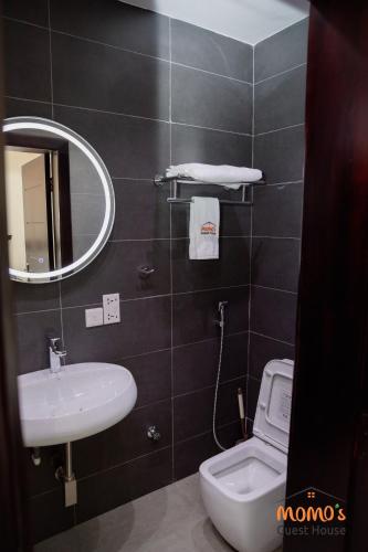 a bathroom with a sink and a toilet and a mirror at Momo's Guest House in Kumasi