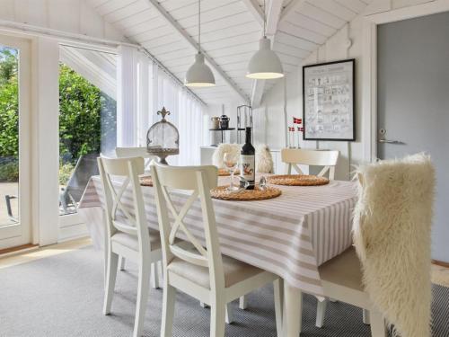 a white dining room with a table and chairs at Holiday Home Helke - 30km from the sea by Interhome in Arrild