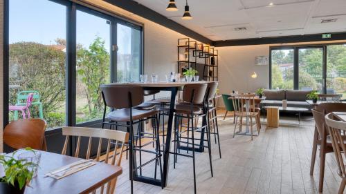 a restaurant with tables and chairs and windows at Campanile NATURE - Bordeaux Sud Gradignan Talence in Gradignan