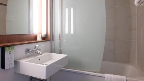 a bathroom with a sink and a shower and a tub at Campanile NATURE - Bordeaux Sud Gradignan Talence in Gradignan