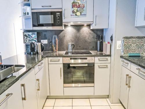a kitchen with white cabinets and a stove top oven at Apartment Residenz Marina-63 by Interhome in Bouveret
