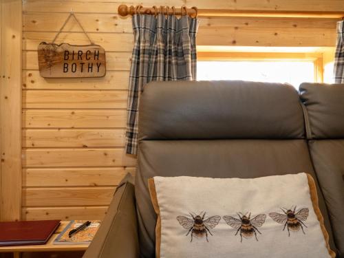 a bed in a tiny house with a honey bee pillow at Apartment Birch Bothy by Interhome in Coldstone