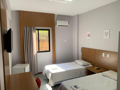 a hotel room with two beds and a television at Hotel Rinkao in Cachoeiro de Itapemirim