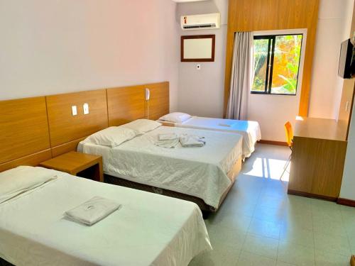a hotel room with two beds and a window at Hotel Rinkao in Cachoeiro de Itapemirim