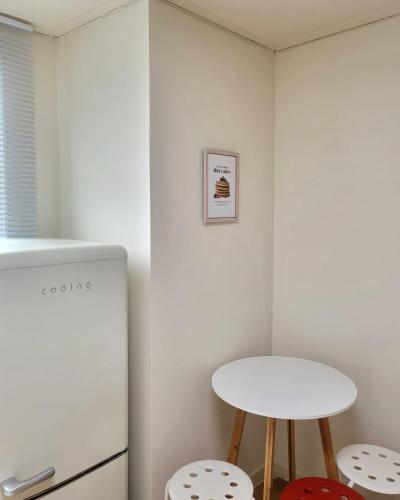 a small kitchen with a white refrigerator and two stools at jeonju hotel book and type in Jeonju