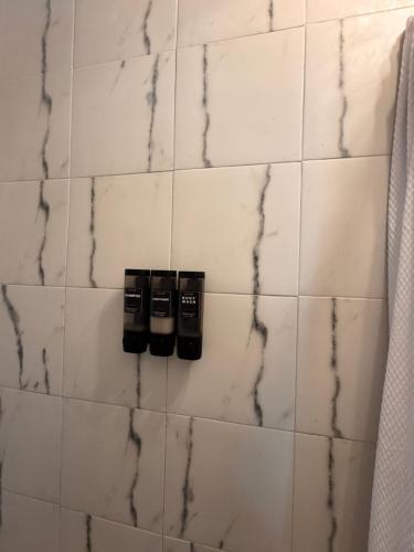 a white tiled bathroom with two black soap bottles at Estancias Nava #1 in San Antonio