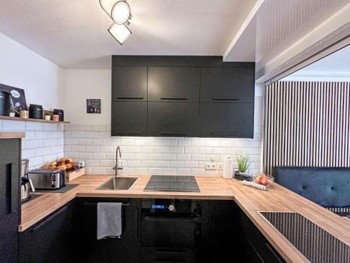 een keuken met zwarte kasten en een spoelbak bij Apartment Ringstrasse - Utoring-64 by Interhome in Leukerbad
