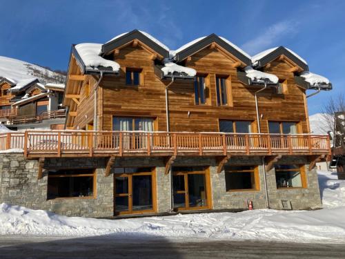 a log home with a deck in the snow at Chalet Salt Lake in La Toussuire