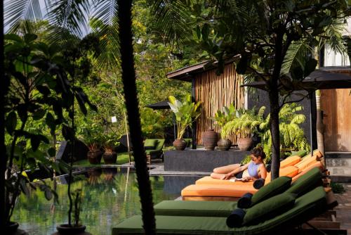 a woman sitting on a couch next to a swimming pool at Sumba Lodge in Manuel Antonio