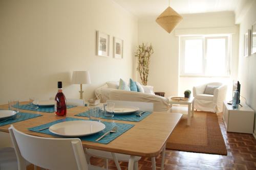 a living room with a table with chairs and a couch at Apartment House in Costa da Caparica