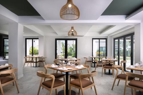 ein Restaurant mit Tischen und Stühlen und Fenstern in der Unterkunft Negril Footeprints Hotel in Negril