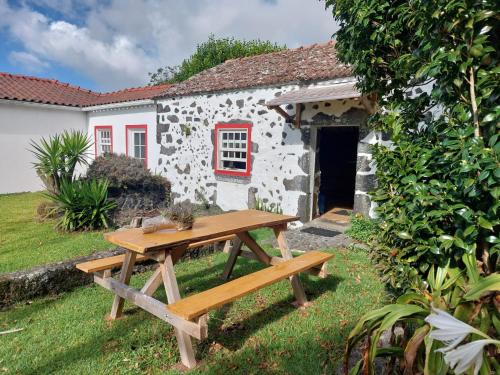 a picnic table in front of a stone cottage at Casa Farrobo in Horta