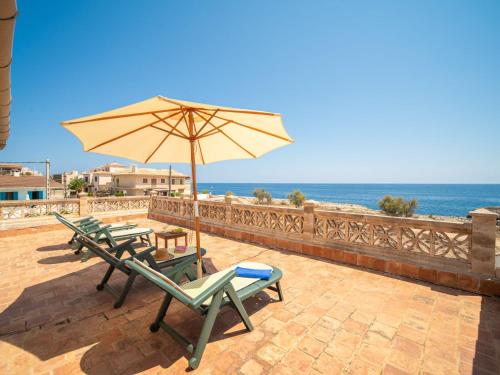 einen Tisch und Stühle mit einem Sonnenschirm und dem Meer in der Unterkunft Holiday Home Villa Can Rosito by Interhome in S'Illot