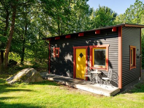 a small cabin with a deck with a table and chairs at Holiday Home Stenlycke by Interhome in Ivö