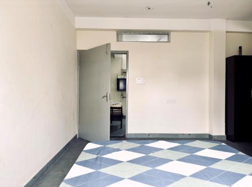an empty room with a door and a checkered floor at Maria's Homestay in Siliguri