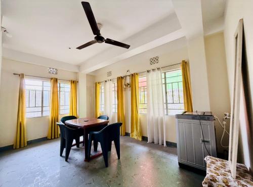 a dining room with a table and chairs and windows at Maria's Homestay in Siliguri