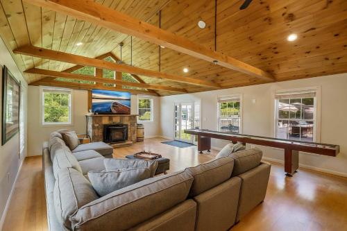 a living room with a couch and a ping pong table at Gilford Getaway - Pool & Hot Tub - Lakes Region in Gilford
