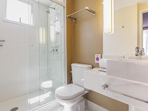 a bathroom with a toilet and a shower and a sink at Mercure Sao Paulo Vila Olimpia in São Paulo