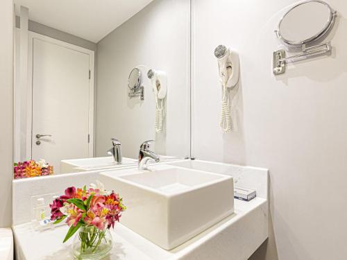 a white bathroom with a sink and a mirror at Mercure Sao Paulo Vila Olimpia in São Paulo