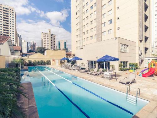 a large swimming pool with chairs and umbrellas at Mercure Sao Paulo Vila Olimpia in São Paulo