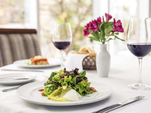 a table with a plate of salad and wine glasses at Mercure Sao Paulo Vila Olimpia in São Paulo