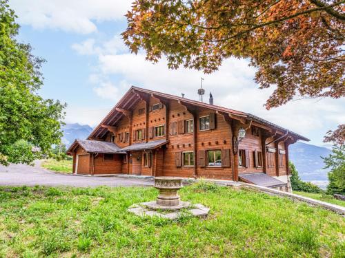 ein großes Holzhaus mit einem Brunnen davor in der Unterkunft Chalet Champ de Brent by Interhome in Huémoz