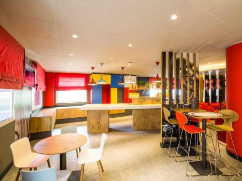 a restaurant with colorful walls and tables and chairs at Ibis Barcelona Castelldefels in Castelldefels