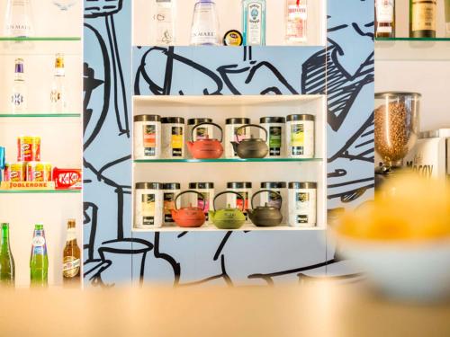 a refrigerator with pots and pans on a wall with graffiti at Ibis Barcelona Castelldefels in Castelldefels