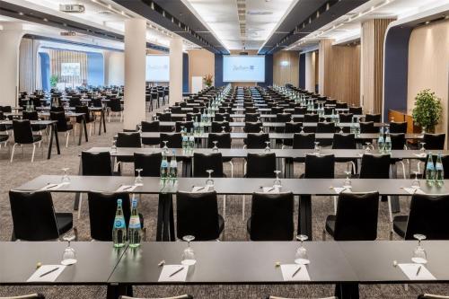 a conference room with tables and chairs and a screen at Radisson Blu Hotel, Hamburg in Hamburg