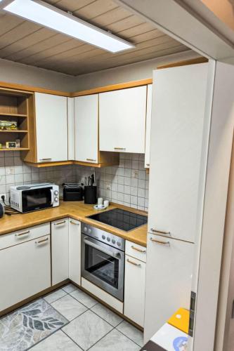 a kitchen with white cabinets and a stove top oven at Holiday Home Ferienhaus Inge & Henry an der Werra by Interhome in Altenburschla