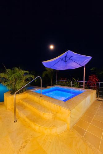 a swimming pool with a purple umbrella next to it at Casa Campestre - Pet Friendly - Green Energy in Anapoima
