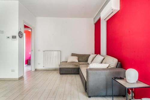a living room with a couch and a red wall at Elegante Appartamento con Comfort Completi vicino a Mezzi & Servizi in Bareggio