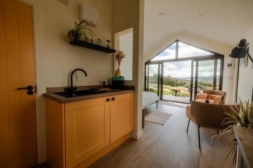 a kitchen with a sink and a table and a window at Oaklane Glamping Cabins in Kenmare