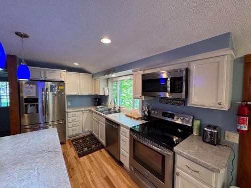 a kitchen with white cabinets and stainless steel appliances at Blue Lake Cottage - 10 Minutes to Minocqua in Minocqua