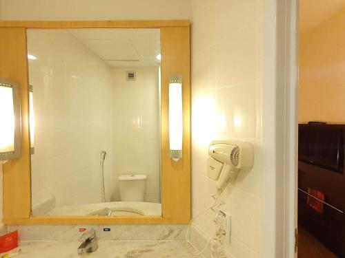 a bathroom with a mirror and a phone on a wall at ibis Manaus Distrito Industrial in Manaus