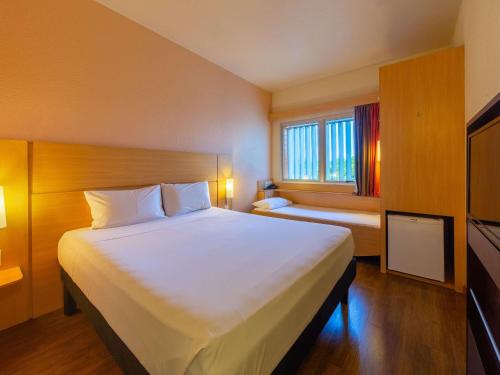 a bedroom with a large white bed and a window at ibis Manaus Distrito Industrial in Manaus
