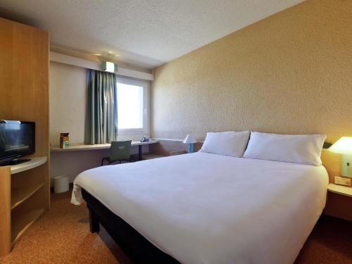 a hotel room with a large bed and a television at Hotel ibis Guimaraes in Guimarães