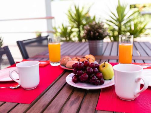 a table with a plate of fruit and two cups of orange juice at Hotel ibis Guimaraes in Guimarães
