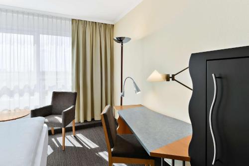 a hotel room with a desk and a bed and a table at NH Mannheim Viernheim in Viernheim