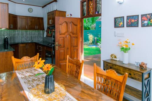 a kitchen with a wooden table with a vase of flowers at Serenity Villa in Madurugomuwa