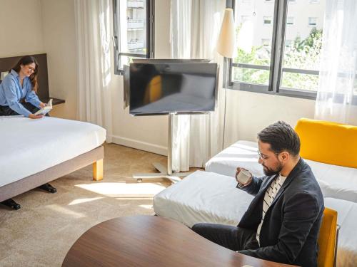 a man sitting at a table in a hotel room at Novotel Suites Paris Montreuil Vincennes in Paris