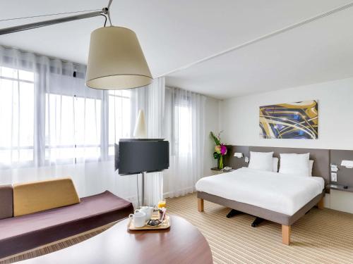 a hotel room with a bed and a couch at Novotel Suites Paris Montreuil Vincennes in Paris