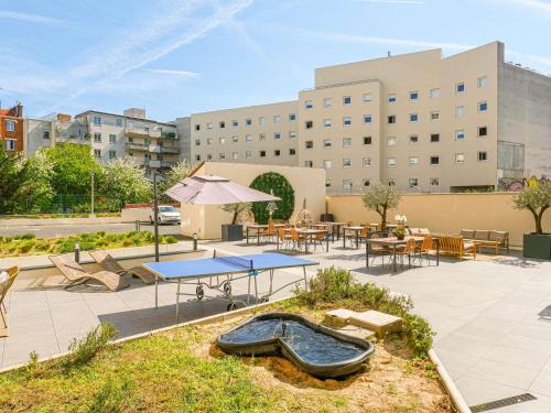 a patio with tables and chairs and a pool at Novotel Suites Paris Montreuil Vincennes in Paris