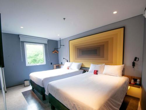 two beds in a room with blue walls and a window at Ibis Monterrey Aeropuerto in Monterrey