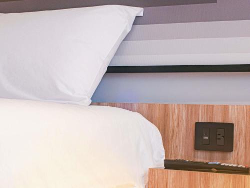 a bedroom with a bed with a white pillow at Ibis Monterrey Aeropuerto in Monterrey